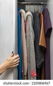  a woman hand opens the sliding door of a wardrobe with clothes.High quality photo