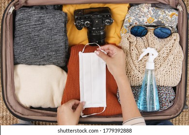 Woman Hand Packing Suitcase Luggage Including Face Mask And Sanitizer To Protect Coronavirus Covid-19, Travel New Normal Concept, Topview