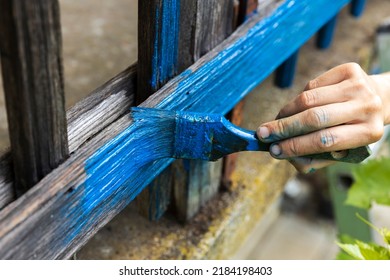 Woman Hand Painting In Blue Tint An Old Wooden Fence