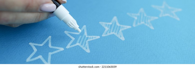 Woman Hand Painting Over Stars On Blue Paper For Evaluating Work Closeup