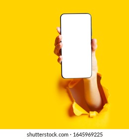 Woman hand in the paper hole holding smartphone. Mobile application.