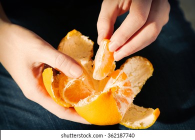 Woman hand peeling ripe sweet tangerine, close up - Powered by Shutterstock