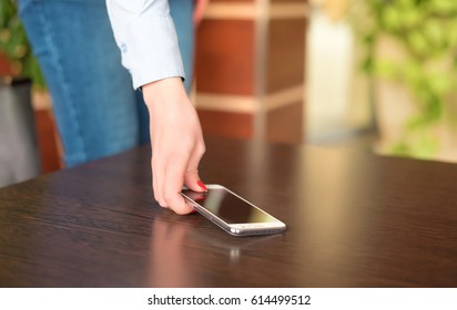 Woman Hand Pick Up The Cellular Phone From The Table