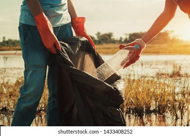 woman hand picking up garbage plastic for cleaning at river                                