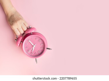 Woman Hand Is Picking Up Pink Alarm Clock. Time Management.