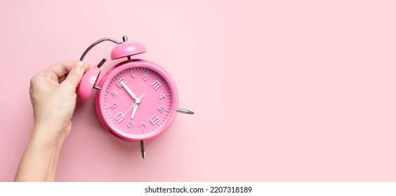 Woman Hand Is Picking Up Or Put Pink Alarm Clock. Time Management.