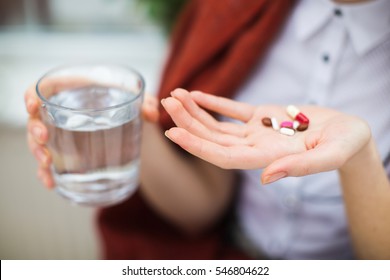 Woman hand with pills medicine tablets and glass of water 