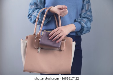 woman hand pink bag with wallet on grey background
