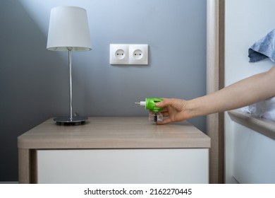 Woman Hand Plugs Mosquito Repellent Into The Socket Before Going To Bed. Domestic Electric Raptor Fumigator For Mosquitoes Protection At Home. 