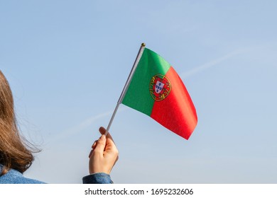 Woman hand with Portuguese swaying flag on the blue sky. Portugal. Concept