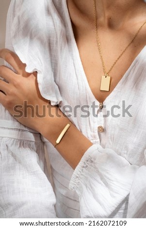 Woman hand posing showing her bracelet and pendant necklace. Women's hand with gold bracelet. Still life photo, minimalism
