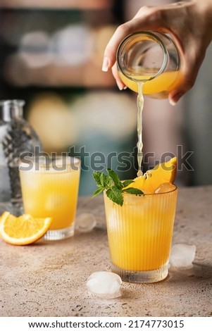 Woman hand pour juice into a cocktail glass filled with an alcoholic drink in pub. Alcoholic soft drink in nightclub. Vertical orientation