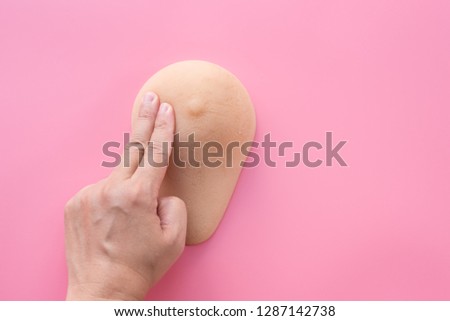 Woman hand practice checking breast model and pink ribbon on pink background.Health education for breast self exam (BSE).Breast cancer awareness and self check, healthy lifestyle concept.