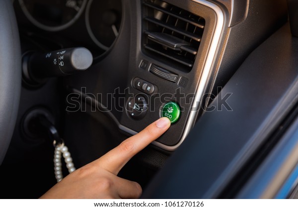 Woman Hand is Pressing Eco Mode Botton in Vehicle
Car, Close-Up of  Female Hand is Pushing Ecology Saving Energy
Function for Personal Transport. Power Save Engine and Pollution
Environment Concept