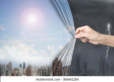 Woman hand pulling open sunny sky cityscape curtain covering stormy city.