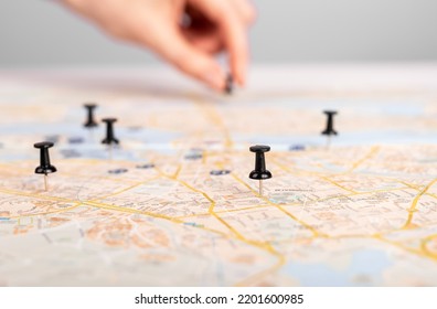 Woman hand pushing pin on map. Trip route planning, events schedule. Female marking travel itinerary with pushpins. High quality photo