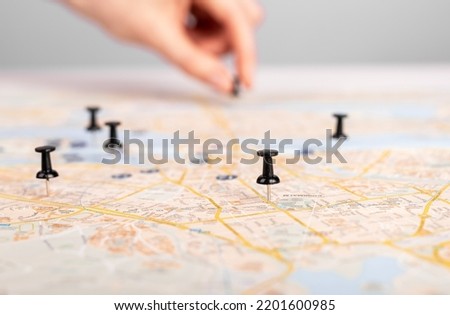 Woman hand pushing pin on map. Trip route planning, events schedule. Female marking travel itinerary with pushpins. High quality photo