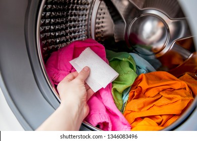 Woman hand put color absorbing sheet inside a washing machine, allows to wash mixed color clothes without ruining colors concept.