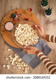 Woman Hand Put Popcorn Bowl On The Table Top View