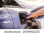 Woman hand puts the car on EV charging. Electric car