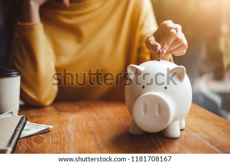 woman hand putting money coin into piggy for saving money wealth and financial concept.