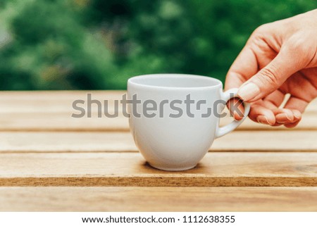 Similar – Foto Bild Frau Hand, die eine Tasse Kaffee von einem Holztisch im Garten aufzieht.