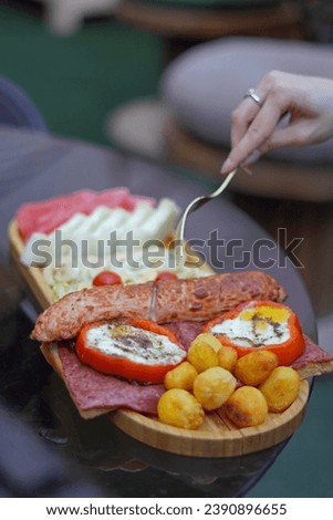 Woman Hand Reaching for Fastfood with Fork, the Food is Placed on a Wooden Plate.