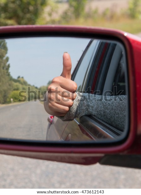 Woman hand with reflection in the view mirror\
(focus mirror). Shallow depth of field. Freedom concept. Lifestyle.\
Travel concept.
