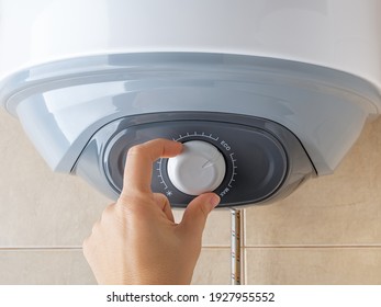 Woman Hand Rotates Water Heater Temperature Adjuster To The Eco Position For Economical Use Of Electricity. Modern Home Appliances With Energy Saving Mode. Domestic Life. Front View.