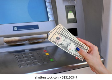 woman hand showing dollar banknotes in front of the atm