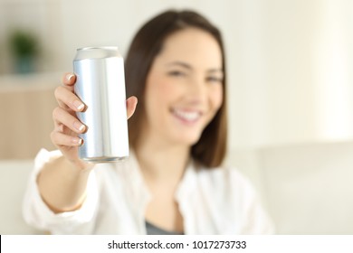 Woman hand showing a soda refreshment can sitting on a couch in the living room at home