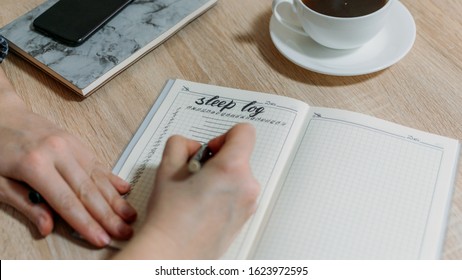 Woman hand with Sleep Log or Diary on table. How to Use a Sleeping Log to Diagnose Insomnia. Identify Sleep Disorders and Poor Sleep Habits.