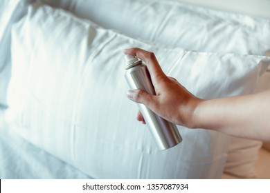 Woman Hand Is Spraying Air Freshener Into Pillow On Bedroom, Close-Up Of Woman Hand Is Holding Bottle Of Air-Freshener Spray Container While Application Into A Pillow Fabric. Home Hygienic And Care 