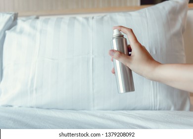 Woman Hand Is Spraying Air Freshener Into Pillow On Bedroom, Close-Up Of Woman Hand Is Holding Bottle Of Air-Freshener Spray Container While Application Into A Pillow Fabric. Home Hygienic And Care 