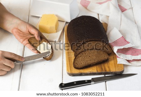 Woman hand spreading butter on sliced bread. Riga rye bread and butter