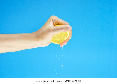 woman Hand Squeezing a Half fresh Lemon isolated on blue background