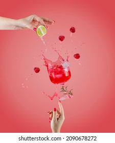 Woman hand support fly glass of raspberry drink with splash, juice raspberry falling in glass. Cocktail of raspberry, lime and rosemary flavor. Summer art food concept on pink background