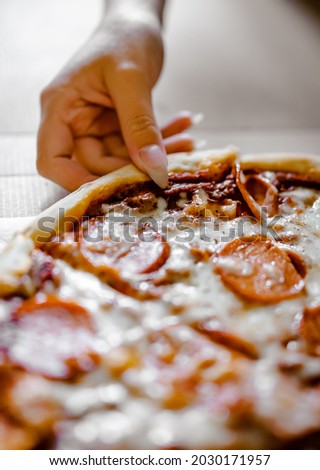 woman Hand takes a slice of Pepperoni Pizza