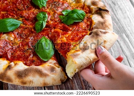 woman Hand takes a slice of Pepperoni Pizza