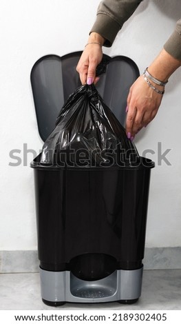 Woman hand taking bag from garbage bin at home. Close up caption. Vertical