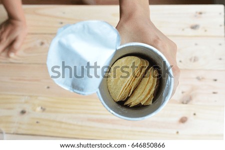 Woman hand taking chips potatoes from can