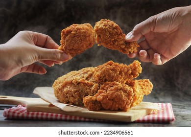 Una mujer cogiendo a mano las alas fritas de pollo con las manos sobre un fondo oscuro con espacio de copia.