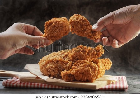 Woman hand taking the fried chicken wings by hands over dark background with copy space.