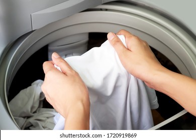 Woman hand taking wet white clothes out of automatic washing machine.