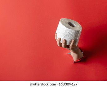 Woman Hand Through Paper Wall Holding Toilet Paper Roll. Toilet Paper Worldwide Panic Buying.