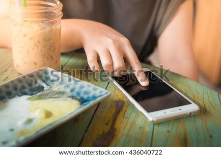 Woman hand touching on smartphone screen in cafe on weekend afternoon