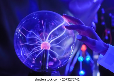 Woman Hand Touching Plasma Ball With Many Energy Rays Inside In Dark Room Of Immersive Museum Or Exhibition- Close Up View. Electricity, Education, Science, Futuristic And Physics Concept