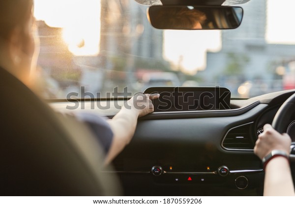 Woman hand touching screen in car while her\
friend is driving