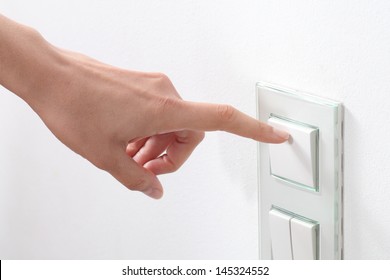 Woman hand turning on the light with a wall switch