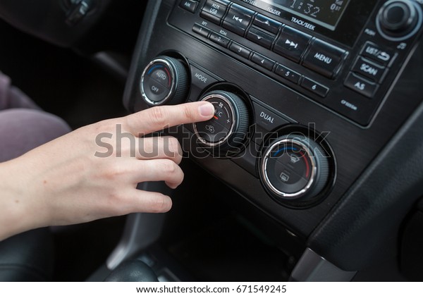Woman
hand turns on air conditioning in a car close
up